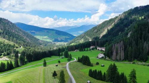 Camera panning over picturesque valley revealing houses and forest