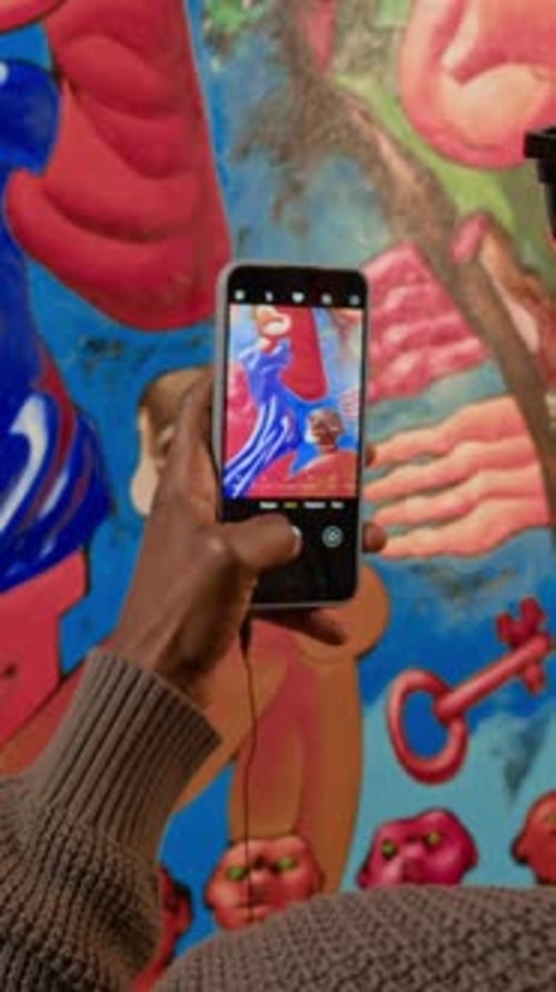 Vertical de un visitante de la galería tomando una foto de una obra de arte en exhibición