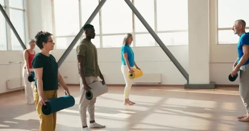 Adults Prepare for Yoga Class in Studio