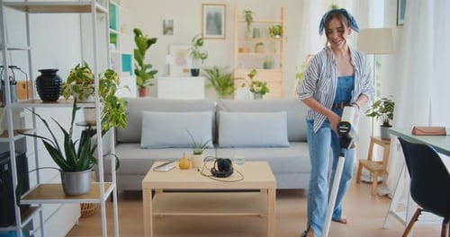 Young Woman Vacuuming in a Bright Apartment