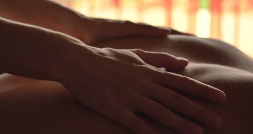 Ein wunderschönes junges Mädchen (Frau) bei einer Rückenmassage im Spa-Salon, eine romantische Kulisse, ein rosafarbenes F