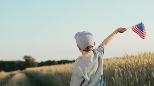 Boy Waves American Flag in Golden Wheat Field