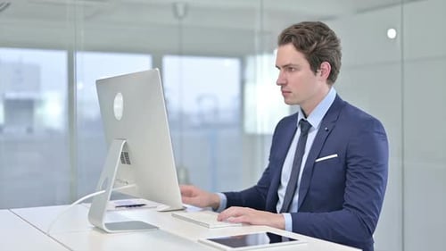 Focused Young Businessman Working on Desktop in Office