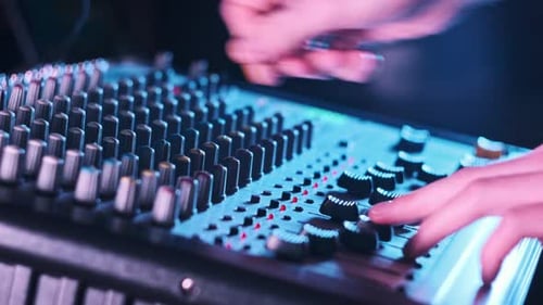 Hand Settings Volume Level Controls on Mixing Console Faders Neon Light CloseUp