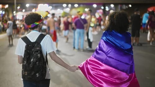 Couple Holds Hands at a Pride Celebration at Night