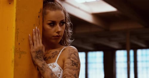 Blonde Woman with Tattoos Posing near Yellow Pillar