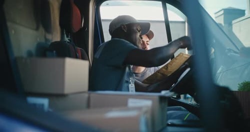 Delivery Truck Driver Sitting in Car Using Digital Tablet Taking Parcel From Colleague