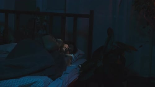 Woman in Bed Using Handheld Device at Night