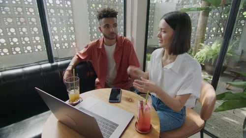 Business Partners Using Laptop while Catching Up in Cafe