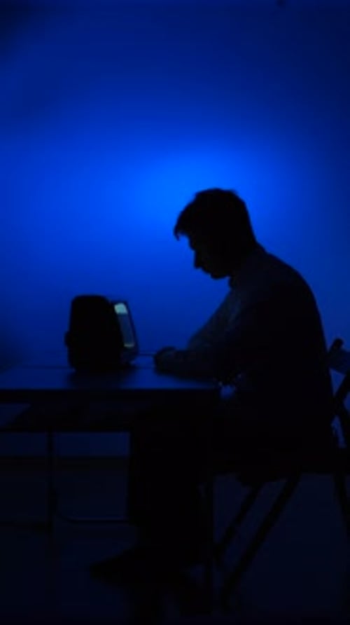 Vidéo verticale : silhouette d'homme regardant une vieille télévision vintage tard dans la nuit avec une lumière bleue