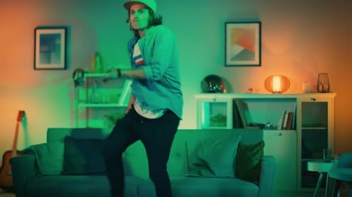 Handsome Excited Hip Young Man is Dancing in the Living Room while TV Plays in the Background. He i