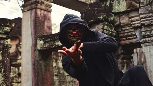 Masked Figure Practices Sword Fighting at Temple Ruins