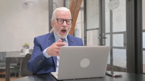 Senior Man Celebrates Success at Workplace with Laptop