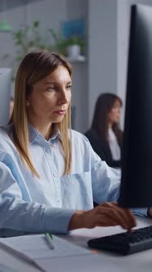 Focused Young Professional Woman Working at Computer in Modern Office Taking Notes and Typing While
