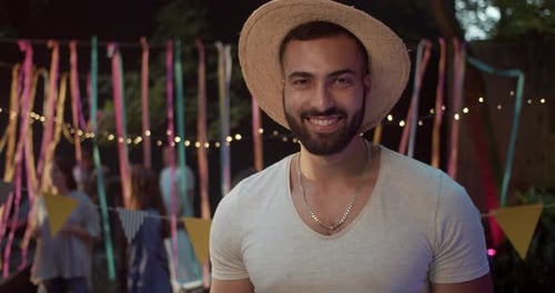 Smiling man in straw hat at party at night