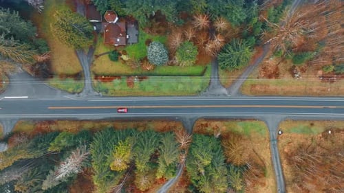 Red automobile rides by the highway in the countryside.