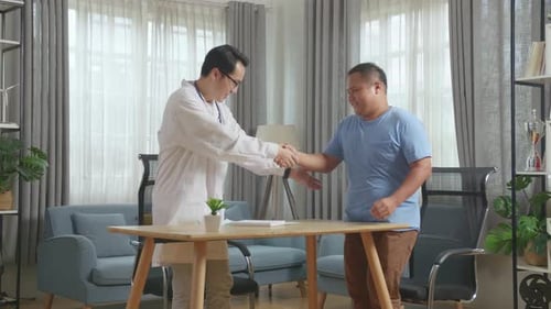 Male Doctor Working On A Tablet Meets Patient In Clinic, Discussing About Medical Check Up