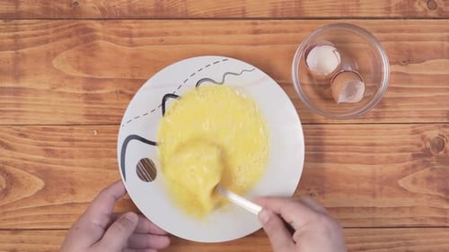 Mixing eggs on the plate to make a delicious omelet. Top view.