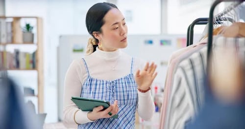 Woman Browsing Clothes Using Tablet in Retail Store