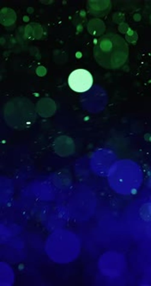 Swirling Particles In Green And Blue Against A Black Background