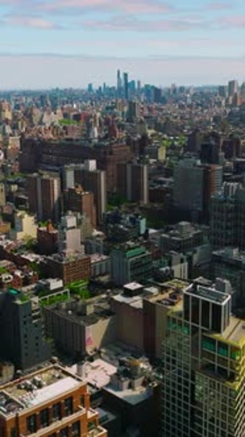 Lower buildings and blocks of flats in New York. Busy motorways and docks near the river.