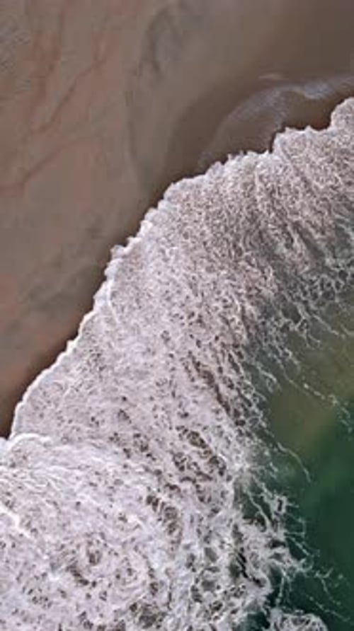 Aerial View of Waves Crashing on a Sandy Shore Surface Ocean Waves Beach