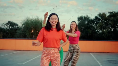Female Friends Holding Sparklers and Roller Skating Together