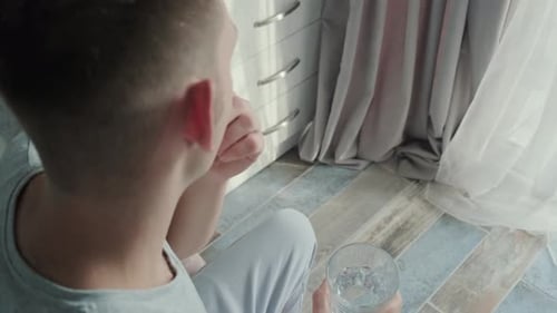 Young Man Taking Pill with Glass of Water