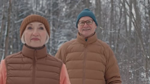 Senior Couple Talking while Nordic Walking in Winter Forest