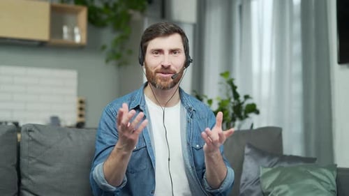 Webcam view of business coach talking by video conference in the living room Young confident bearded