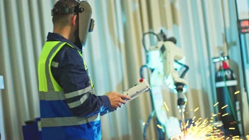Two technician worker or engineer men with welder mask support work together and stand front robot