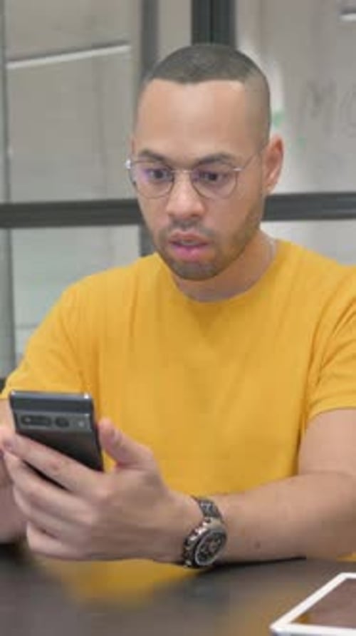 Hispanic Man Celebrating Success on Phone in Office, vertical video