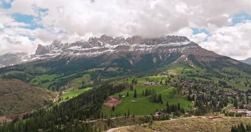 Experience a Picturesque Mountain Village with Green Hills Cloudy Sky