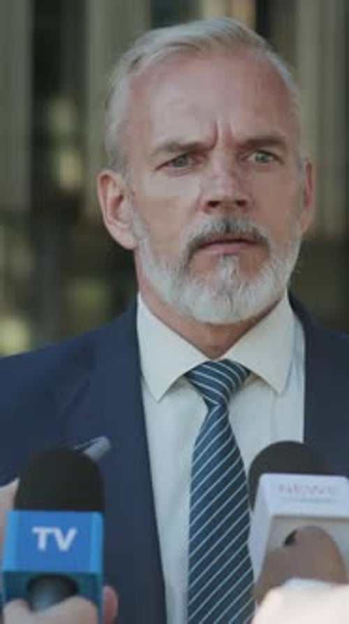 Man Giving Press Conference Interview in Gray Suit