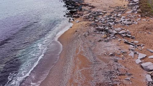 Scenic view of rocky beach beside calm ocean water at sunset
