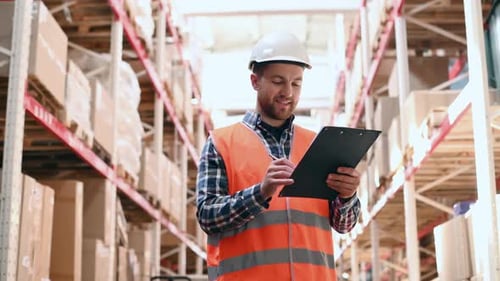 Holding tablet. Storage worker in uniform is in the warehouse