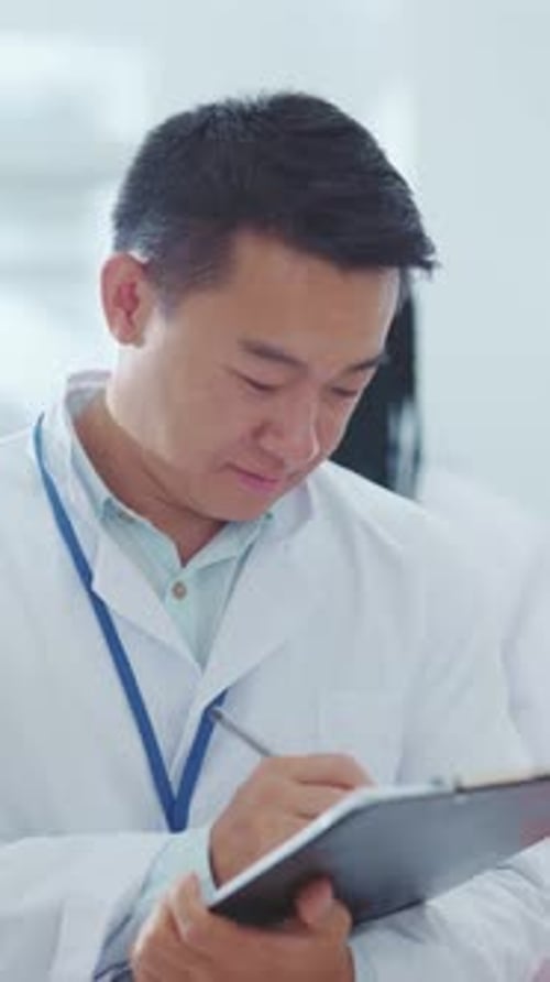 Young Doctor Writing on Clipboard Smiling Portrait