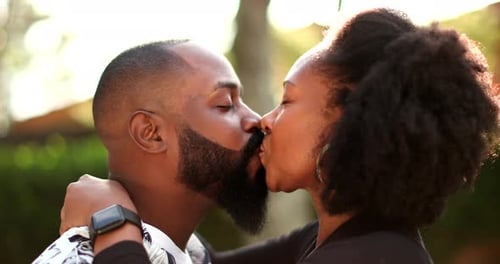 Affectionate Couple Kissing and Embracing in Sunny Outdoor Setting