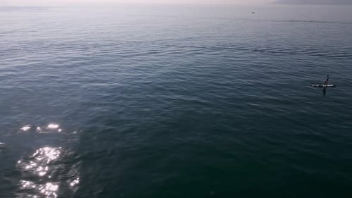 Aerial View of a Man Paddling a Standup Paddleboard or SUP Board on a Calm Sea