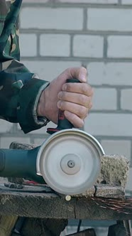 Builder in Work Wear corta varillas de metal con una sierra de disco manual
