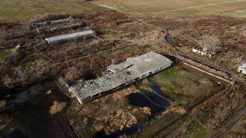 Aerial shot of the destroyed cattle barn and explosion crater, real war in Ukraine