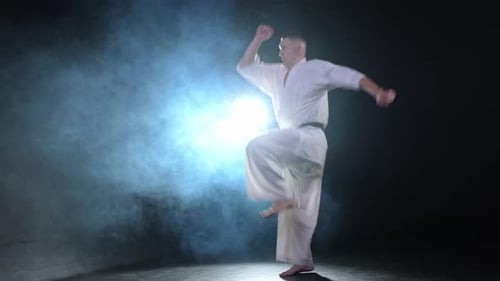Starker Kämpfer im weißen Kimono für Karate-Kampfkünste mit schwarzem Gürtel bereitet sich auf den Kampf vor