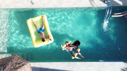 Friends at swimming pool aerial drone view of people that swim at pool floating over inflatable bed