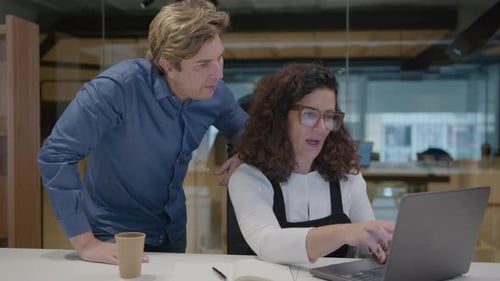 Man Helping Colleague with Laptop in Office
