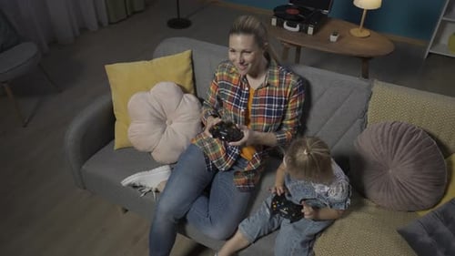 Top View of Mom and Young Daughter Playing Video Games with Joysticks Close Up Mom and Daughter