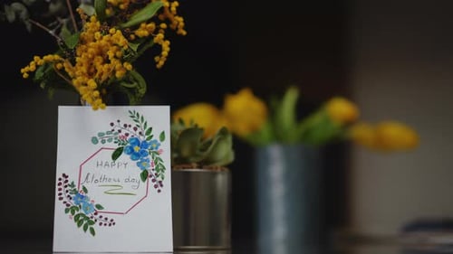 Closeup A Bouquet of Spring Flowers with a Mother's Day Card Stands on a Table Indoors