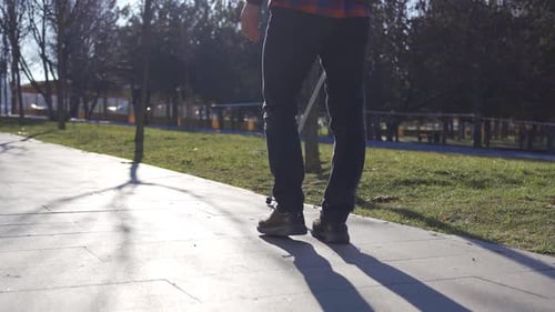 Close-up of blind man's feet and cane walking on a path among trees.