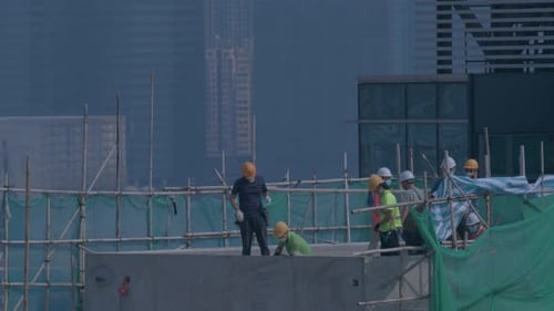 Builders On The Roof Of A High Rise Building Under Construction In Hong Kong