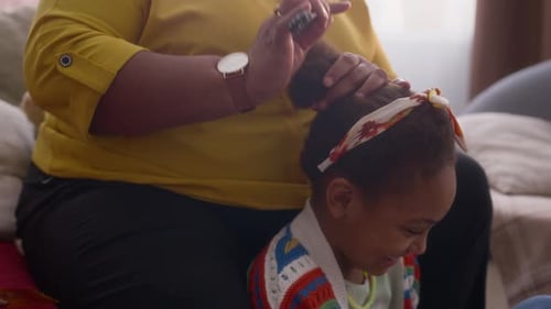 Woman Combs Little Girl's Hair at Home
