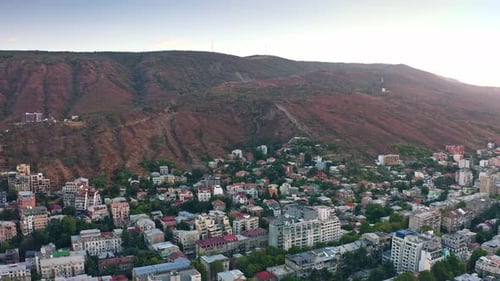 Mountain range and residential districts of Tbilisi at dawn, view from drone